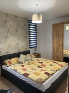 a bedroom with a bed with a quilt on it at Marcipán Apartman in Balatonlelle