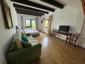 a living room with a couch and a bed and a desk at Pensiunea La Maison in Bran