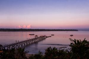 a dock on a body of water at sunset at The Oberoi Beach Resort, Lombok in Tanjung