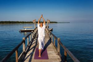 a man doing yoga on a dock on the water at The Oberoi Beach Resort, Lombok in Tanjung