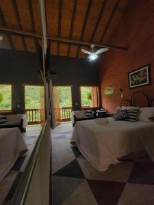 a bedroom with two beds and a ceiling fan at Pousada Sítio das Pedras in Domingos Martins