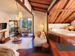 ein großes Wohnzimmer mit einer Badewanne in einem Zimmer mit Holzdecken in der Unterkunft Espaço Verde Novo Chalés in Teresópolis