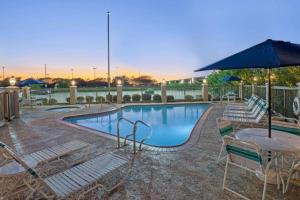 a pool with chairs and a table and an umbrella at Sonesta Essential Houston Westchase in Houston