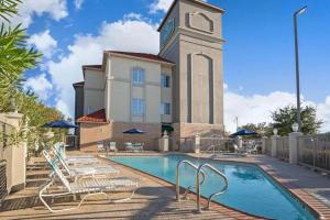 a building with a pool and a clock tower at Sonesta Essential Houston Westchase in Houston