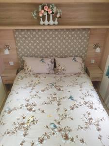 a bed with a white bedspread with flowers on it at The Nook, White Horse, Selsey in Selsey