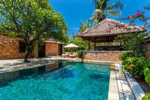 a swimming pool in the backyard of a villa at The Oberoi Beach Resort, Lombok in Tanjung