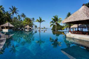 a swimming pool at a resort with palm trees at The Oberoi Beach Resort, Lombok in Tanjung