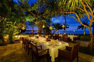 a restaurant with tables and chairs and the ocean at night at The Oberoi Beach Resort, Lombok in Tanjung