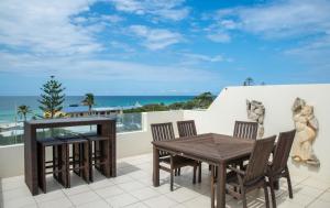 a dining room table with chairs and a balcony at Paradiso Resort Kingscliff in Kingscliff