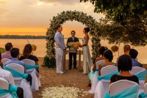 a bride and groom standing in front of a wedding ceremony at The Oberoi Beach Resort, Lombok in Tanjung