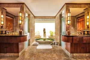 a bathroom with two sinks and a tub at The Oberoi Beach Resort, Lombok in Tanjung