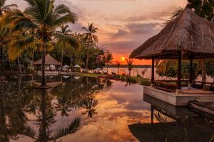 a sunset over a pool at a resort at The Oberoi Beach Resort, Lombok in Tanjung