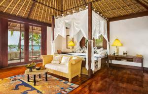 a bedroom with a canopy bed and a living room at The Oberoi Beach Resort, Lombok in Tanjung