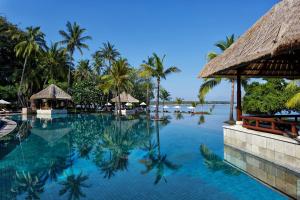una piscina en un complejo con palmeras en The Oberoi Beach Resort, Lombok en Tanjung