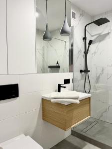a white bathroom with a sink and a shower at Apartament nad Zalewem w lesie in Serock