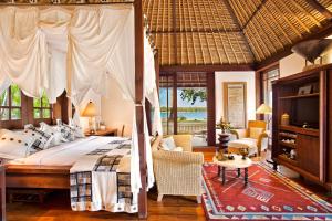 a bedroom with a large bed and a living room at The Oberoi Beach Resort, Lombok in Tanjung