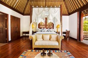a bedroom with a bed with a canopy at The Oberoi Beach Resort, Lombok in Tanjung