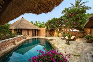 an outdoor swimming pool in a resort with flowers at The Oberoi Beach Resort, Lombok in Tanjung