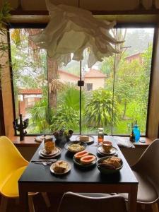 un tavolo con cibo sopra di esso davanti a una finestra di CasAlê Come&Dorme a São Pedro da Serra