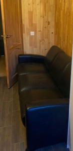 un divano in pelle nera in una stanza con porta di Lauku street private apartment a Liepāja