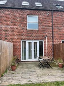 a brick house with a white door and two benches at Family home close to Shrewsbury Town centre in Shrewsbury
