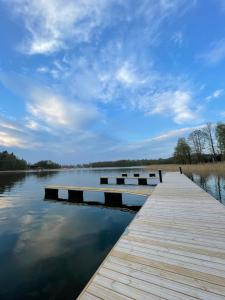 a dock on a body of water with a cloudy sky at Tiny House - Osada Wilkasy in Giżycko