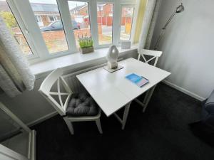 a white table and chair with a lamp and a book at Seaside sanctuary in Pakefield
