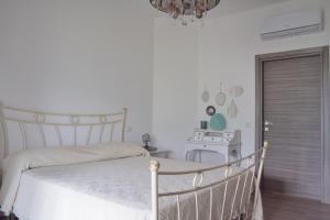 ein Schlafzimmer mit einem weißen Bett und einem Kronleuchter in der Unterkunft La Rosa di Tempalta in Albanella