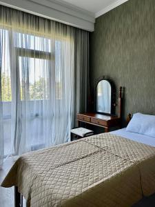 a bedroom with a bed and a desk and a window at Aparthotel Kutaisi in Kutaisi