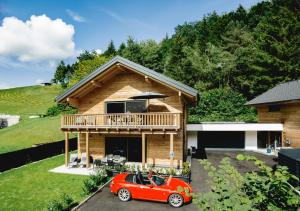 una casa con una piccola auto rossa parcheggiata di fronte di Chalet 49 Nesselgraben - Ferienwohnungen aus Holz a Koppl