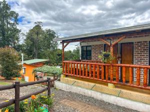 a brick house with a wooden porch and a fence at Campground Hostal La Bonanza Chez Kika in Piendamó