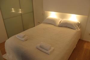a bedroom with a white bed with two towels on it at Moonlight Shadow Apartment in Sarajevo