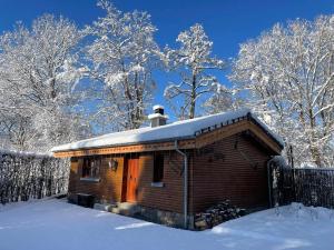 una pequeña cabaña de madera con nieve encima en Le chalet du Hélivy en Jalhay