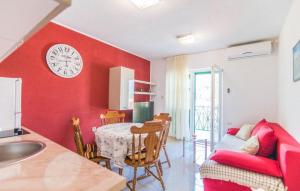 a kitchen with a red wall with a table and a clock at Apartment Ina in Povlja