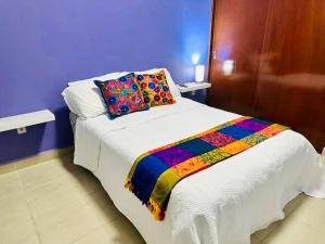 プエルト・モレロスにあるCasa Puerto Morelos Riviera Mayaのベッドルーム(白いベッド、カラフルな毛布付)