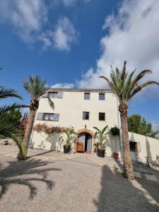 a large white building with palm trees in front of it at Masia Cal Lloa in Albinyana