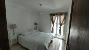 a white bedroom with a bed and a window at Magnifique appartement au centre de Mouans-Sartoux in Mouans-Sartoux