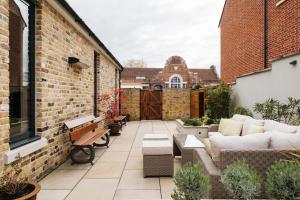 an outdoor patio with a couch and chairs on a brick building at Grand Historical Listed energy efficient retreat Canterbury completely modernised in Canterbury