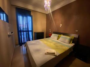 um quarto com uma cama com lençóis amarelos e um lustre em Appartement COQUILLAGE em Skhirat