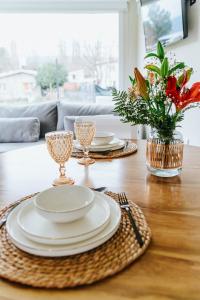 una mesa con platos y vasos y un jarrón de flores en Madero departamentos en El Bolsón