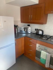 a kitchen with a white refrigerator and wooden cabinets at 2 bed house, walking distance Shrewsbury centre in Shrewsbury