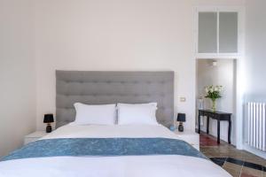 1 dormitorio con 1 cama blanca grande y cabecero gris en Palazzo Dasso, en Viterbo