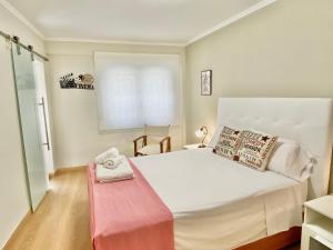 um quarto com uma grande cama branca e um banco vermelho em Apartamento en el Centro, 2 dormitorios, junto parking telpark em Almería