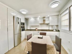 Apartamento en el Centro, 2 dormitorios, junto parking telpark في ألميريا: مطبخ مع طاولة وكراسي وثلاجة