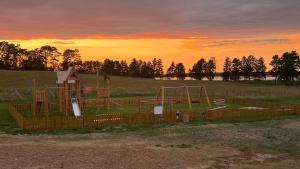 a playground in a field with a sunset in the background at Wioska Wakacyjna Glamila in Sterławki Wielkie