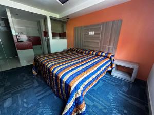 Hotel Rossel Plaza في مدينة ميكسيكو: غرفة نوم بسرير بحائط برتقالي