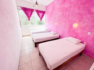 um quarto com duas camas e uma parede rosa em ITH Amazing Hostel Sayulita em Sayulita