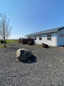 a large rock in a gravel yard next to a building at Strýta 4 in Ölfus