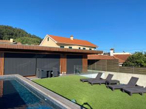 a backyard with chairs and a swimming pool and a house at PEARL by Balgrid in Viana do Castelo