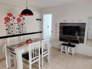 a dining room with a white table and a tv at Luz de Faro, frente a las playas mas lindas! in Mar del Plata